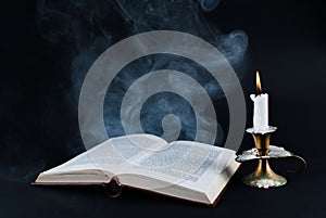 Enigmatic Aura: Smoke, Book, and Candle on Dark Background