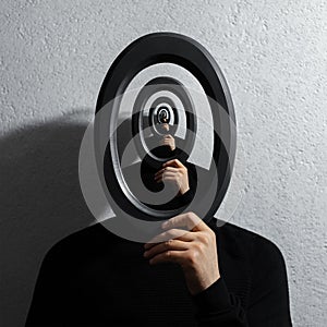Enigmatic surrealistic optical illusion, young man holding round frame on textured grey background.