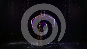 enigmatic woman is dancing traditional oriental dance under rain, belly dance