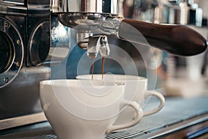 Enjoy barista style coffee. Coffee being brewed in coffeehouse or cafe. Espresso making with portafilter. Coffee cups
