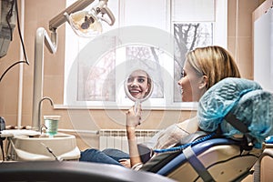 Enjoy the beauty of a healthy smile. Happy dentist patient checking whitening results looking in a mirror