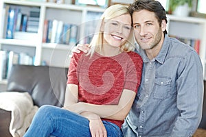 They enjoy being close to each other. Portrait of a young couple sitting together in their living room.