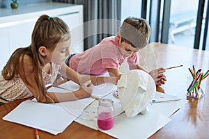 They enjoy getting crafty. two adorable little siblings painting together at home.