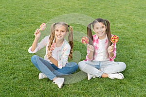 Enjoy these lollipops with taste sensation. Happy children hold lollipops green grass. Eating large swirl lollipops on