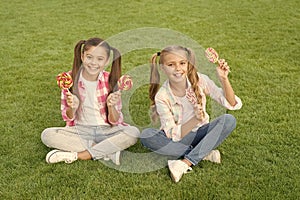 Enjoy these lollipops with taste sensation. Happy children hold lollipops green grass. Eating large swirl lollipops on