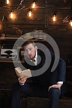 Enjoy moment. Man with beard holds old book and read. Guy in cozy warm atmosphere relaxing while reading. Man in formal