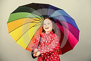 Enjoy rain concept. Fall season. Kid girl happy hold colorful rainbow umbrella. Rainy weather with proper garments