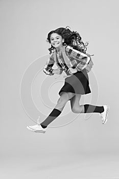 Enjoy school holidays. Happy girl run from school. Little child in midair yellow background. School holidays. Holidays