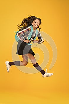 Enjoy school holidays. Happy girl run from school. Little child in midair yellow background. School holidays. Holidays