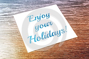 Enjoy your Holidays Reminder On Paper Lying On Wooden Table