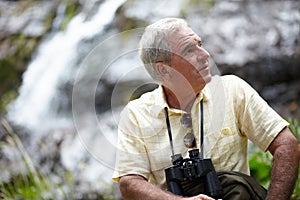 Enjoying the beautiful scenery. a senior man with binoculars looking at the scenery.