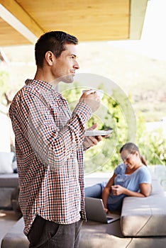 Enjoying the beauty of nature with a few modern comforts. a young man drinking coffee while a woman works on a laptop in