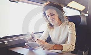 Enjoying business travel concept. Young beautiful brunette tourist girl travelling on the train sitting near the window