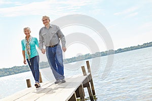 Enjoying a casual stroll. A loving elderly couple wallking along the pier.