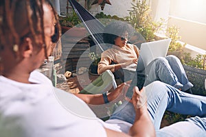 Enjoying a chilled afternoon with their connections. a young woman using a laptop and relaxing on a hammock while her