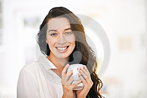 Enjoying a cuppa java joy. Portrait of a happy young woman enjoying a cup of coffee.