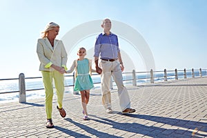 Enjoying a day with the grandparents. grandparents walking hand in hand with their granddaughter on a promanade.