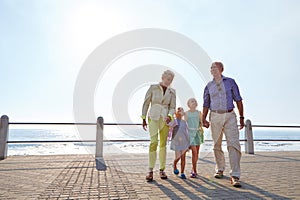 Enjoying a day with their granddaughers. grandparents walking hand in hand with their granddaughters on a promanade.