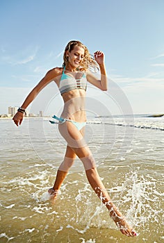Enjoying the feel of cool water on her feet. an attractive young woman running on the beach.