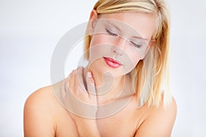 Enjoying the feeling of beautiful skin. Relaxed young woman touching her skin against a white background.