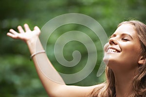 Enjoying the freedom of being in nature. A pretty young woman with her arms raised while standing in a forest.