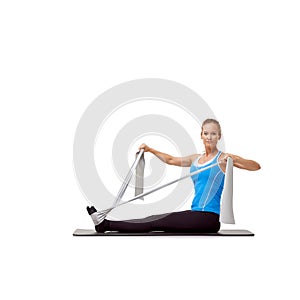 Enjoying her daily workout. A beautiful young woman sitting on a mat and exercising with a resistance band - portrait.