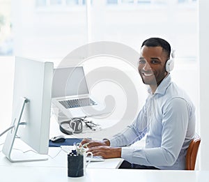 Enjoying his playlist at work. A handsome young african american businessman working at his desk.