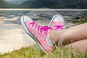 Enjoying by lake. Woman wearing pink sneakers