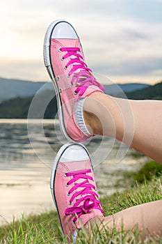 Enjoying by lake. Woman wearing pink sneakers