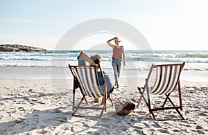 Enjoying a lazy summers day. Rearview shot of a middle aged couple sitting in their beach chairs on the the beach.