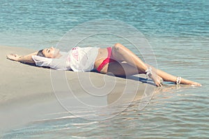Enjoying life beautiful woman lying in wet sand on the beach Sum