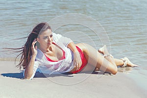 Enjoying life beautiful woman lying in wet sand on the beach Sum