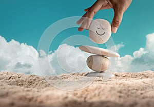 Enjoying Life Concept. Harmony and Positive Mind. Hand Setting Natural Pebble Stone with Smiling Face Cartoon to Balance on Beach photo