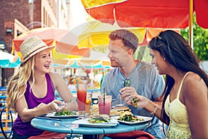 Enjoying a meal with friends. three young friends sitting at an outdoor cafe.