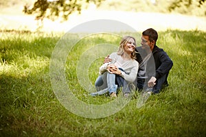 Enjoying a moment away from it all. Shot of a loving young couple sitting on the grass in a park.