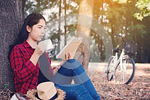 Enjoying moment hipster woman reading a book and sitting under the big tree on park