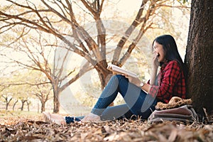 Enjoying moment hipster woman reading a book and sitting under the big tree on park