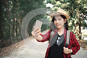 Enjoying moment woman backpacker and selfie in the road and forest background