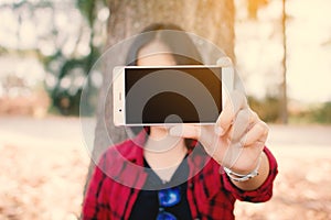 Enjoying moment woman using smartphone sitting under the big tree on park