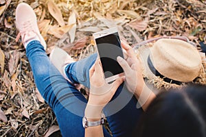 Enjoying moment woman using smartphone sitting under the big tree on park