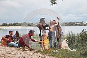 Enjoying the nature. Group of people have picnic on the beach. Friends have fun at weekend time