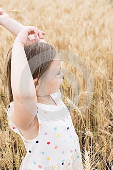 Enjoying the nature. Little girl stay in the golden wheat field