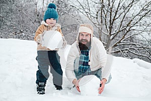 Enjoying nature wintertime. Father and son making snowball on winter white background. Happy family plaing with a