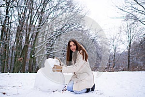 Enjoying nature wintertime. Winter woman happy. Beautiful girl in the winter forest in white down jacket.