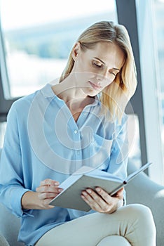 Beautiful young woman reading a book on sofa