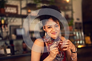 Enjoying a perfect afternoon pick-me-up. Portrait of an attractive young woman enjoying a cup of coffee in a cafe.