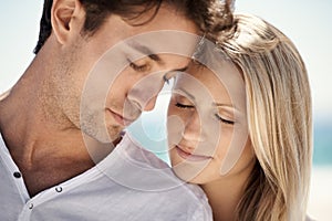 Enjoying a romantic getaway. A young couple having an intimate moment on the beach.