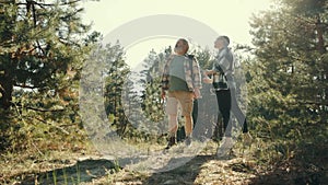 Enjoying. Senior happy couple, man and woman walking in forest on warm sunny day, spending good active time together