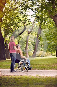 Enjoying senior man in wheelchair and daughter in the park