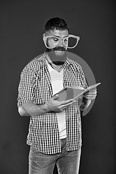 He enjoying the stories. Book nerd wearing fancy glasses. Study nerd reading book. University male student holding